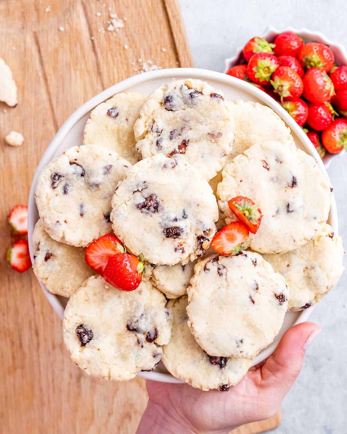 A full plate of baked strawberry cheesecake cookies with golden bottoms and strawberry flecks.