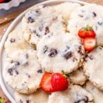 Overhead shot of cookies piled onto a white plate with whole strawberries on the side.