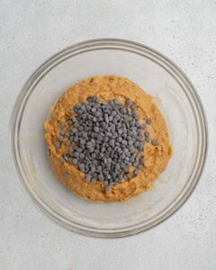 Chocolate chips are added to batter in a bowl.