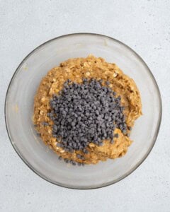 Chocolate chips are added to a bowl with the cookie dough mixture.