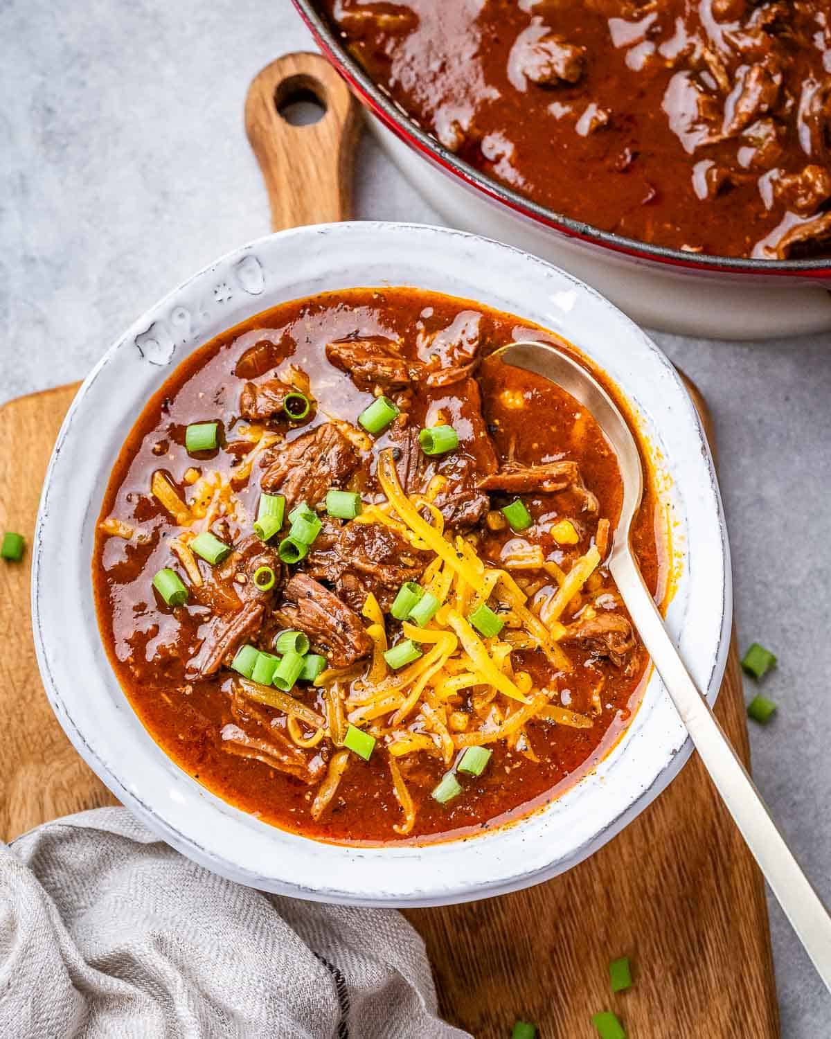 Texas chili in a white bowl on a wooden board