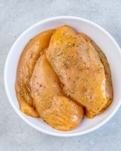 seasoned raw chicken breasts in a bowl.