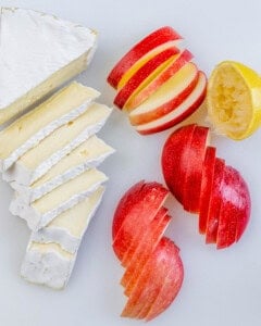 sliced apple and brie on a cutting board.