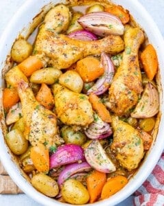 Overhead image of baked chicken legs and vegetables with herbs sprinkled on top for garnish.