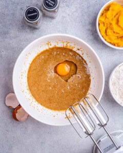 An egg is being mixed with sugar in a bowl.