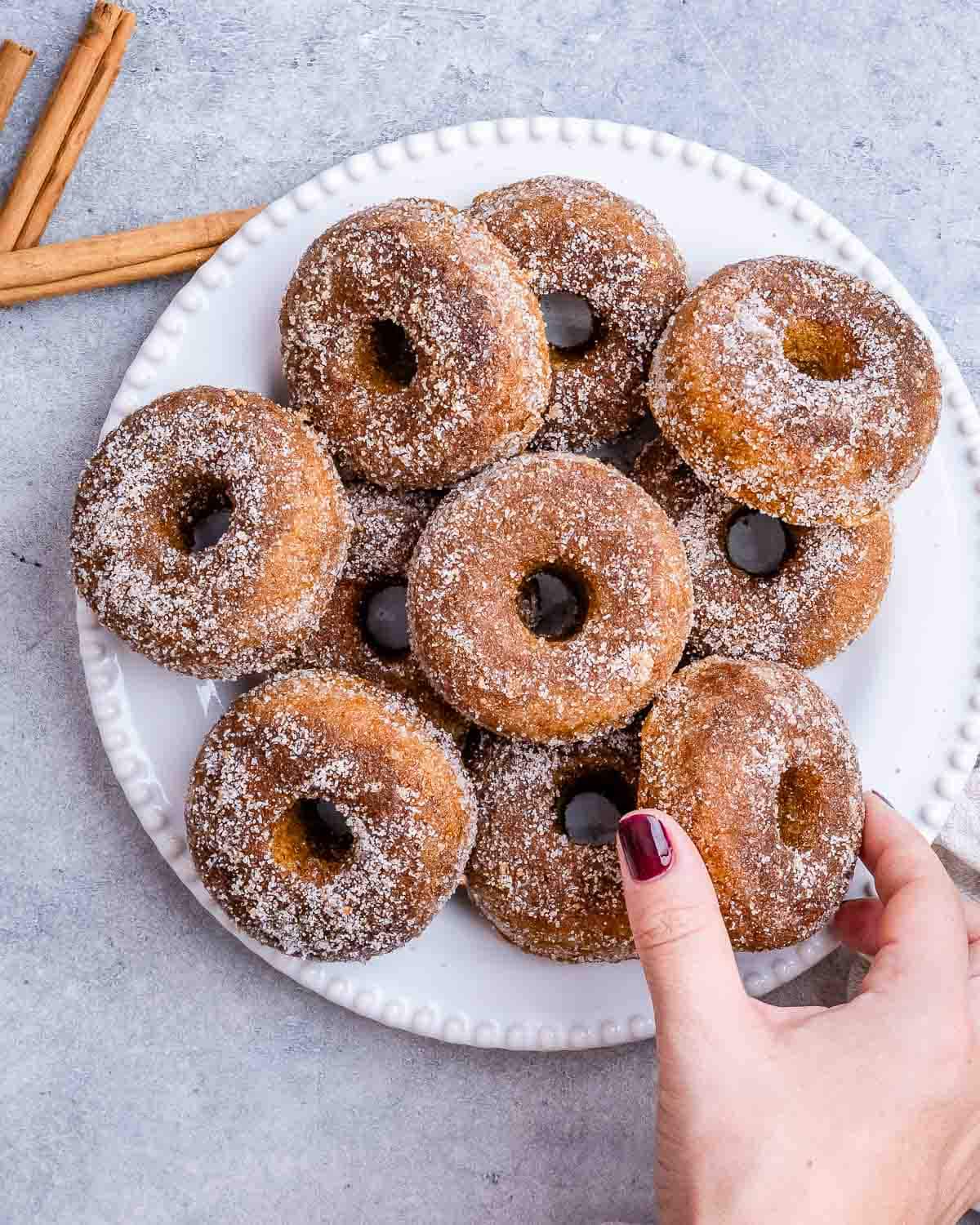 hand grabbing donuts from a plate.