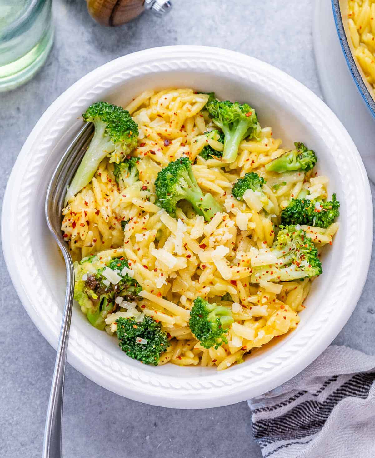 A white bowl with broccoli cheddar orzo.