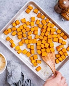 Cubed butternut squash spread evenly on a baking sheet, ready to roast.