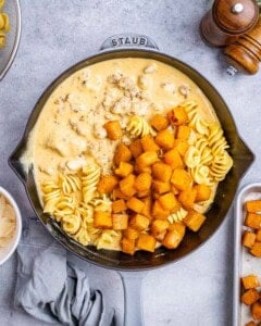 Cooked pasta, roasted butternut squash, and sauce together in a skillet, ready to mix.