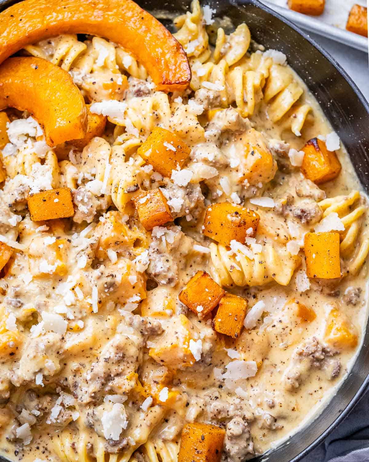 Creamy Butternut Squash Pasta close-up, showing spirals of pasta coated in sauce with tender squash and a sprinkle of cheese.