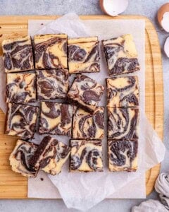 Cheesecake brownies on a cutting board sliced into squares