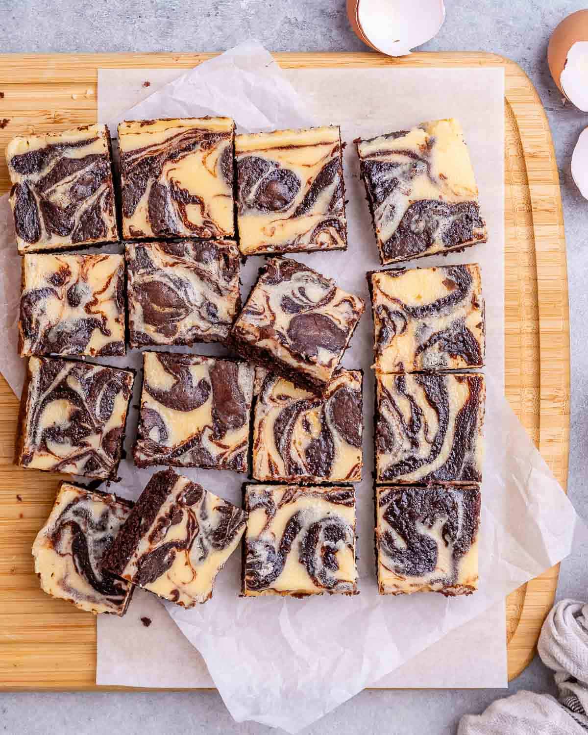 Cheesecake brownies on a cutting board sliced into squares