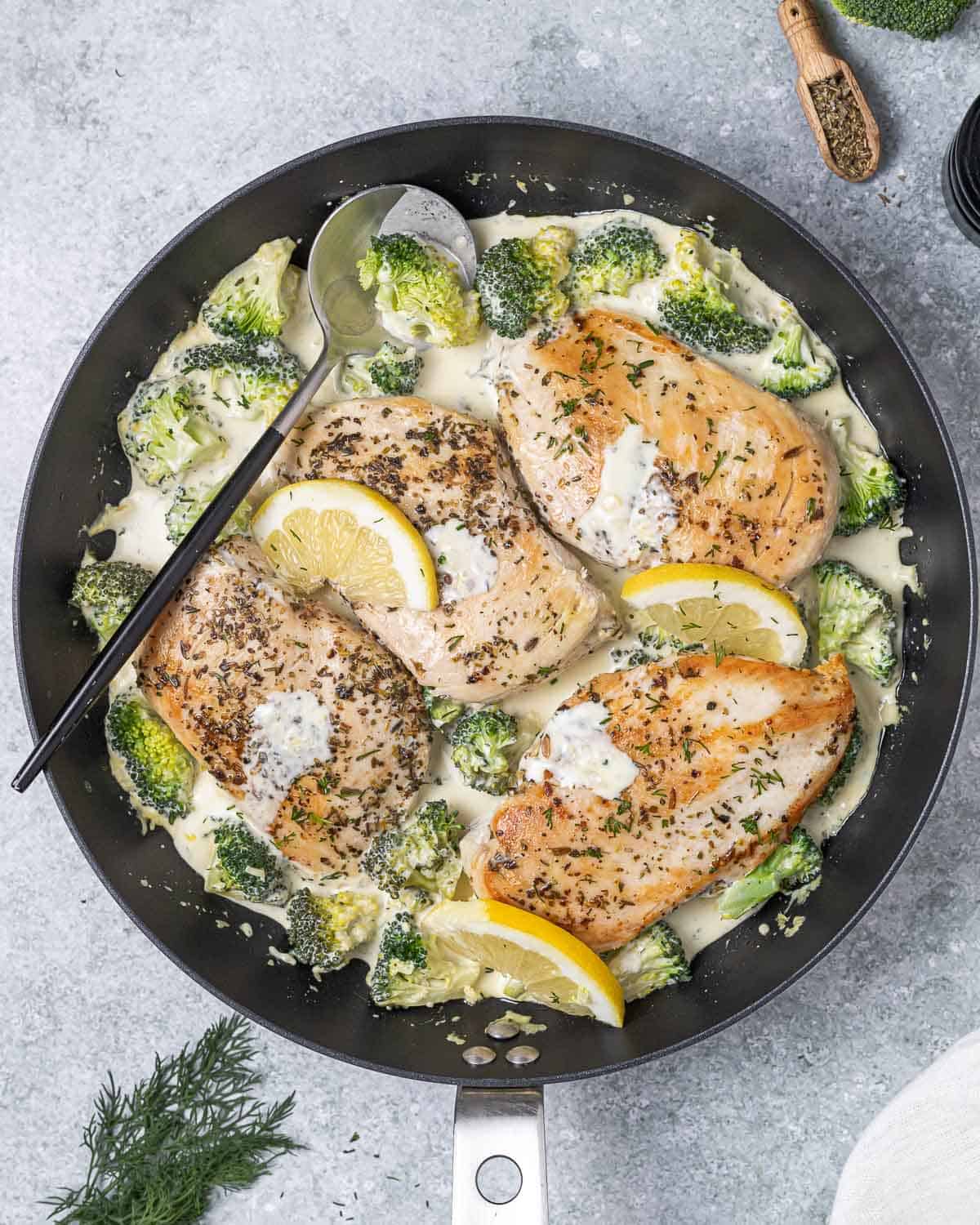 a skillet with creamy seared chicken breast with broccoli.