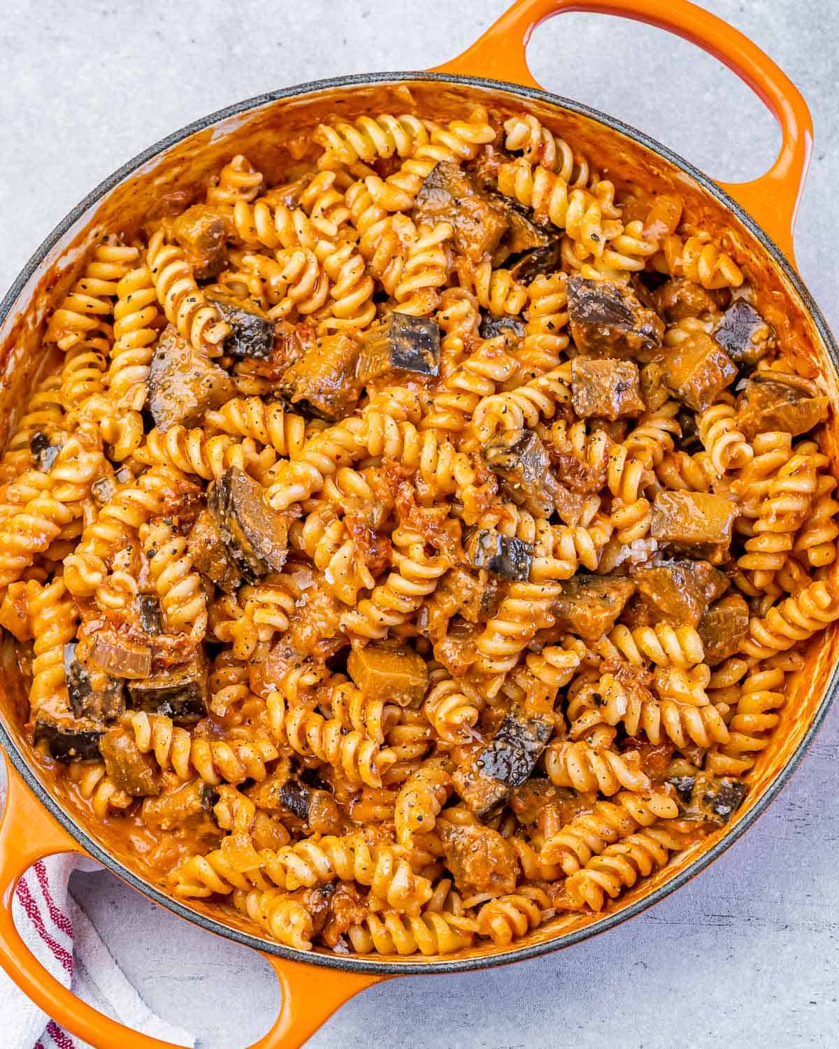 An orange skillet with creamy eggplant pasta.