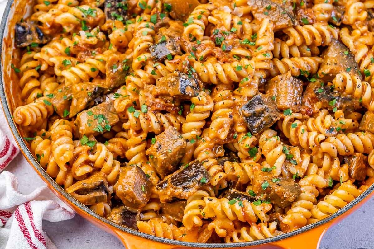 An orange skillet with creamy eggplant pasta.