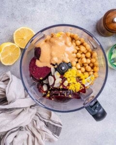 ingredients for beet hummus are added into a blender.