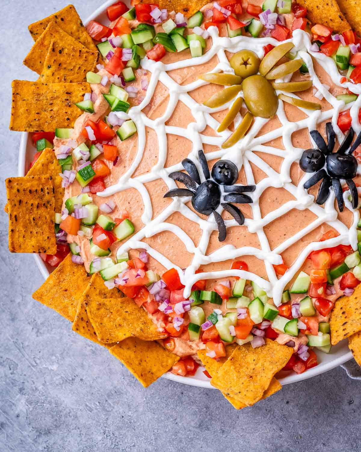 Top view of the decorated taco dip showing the veggie border and tortilla chips around the dish.
