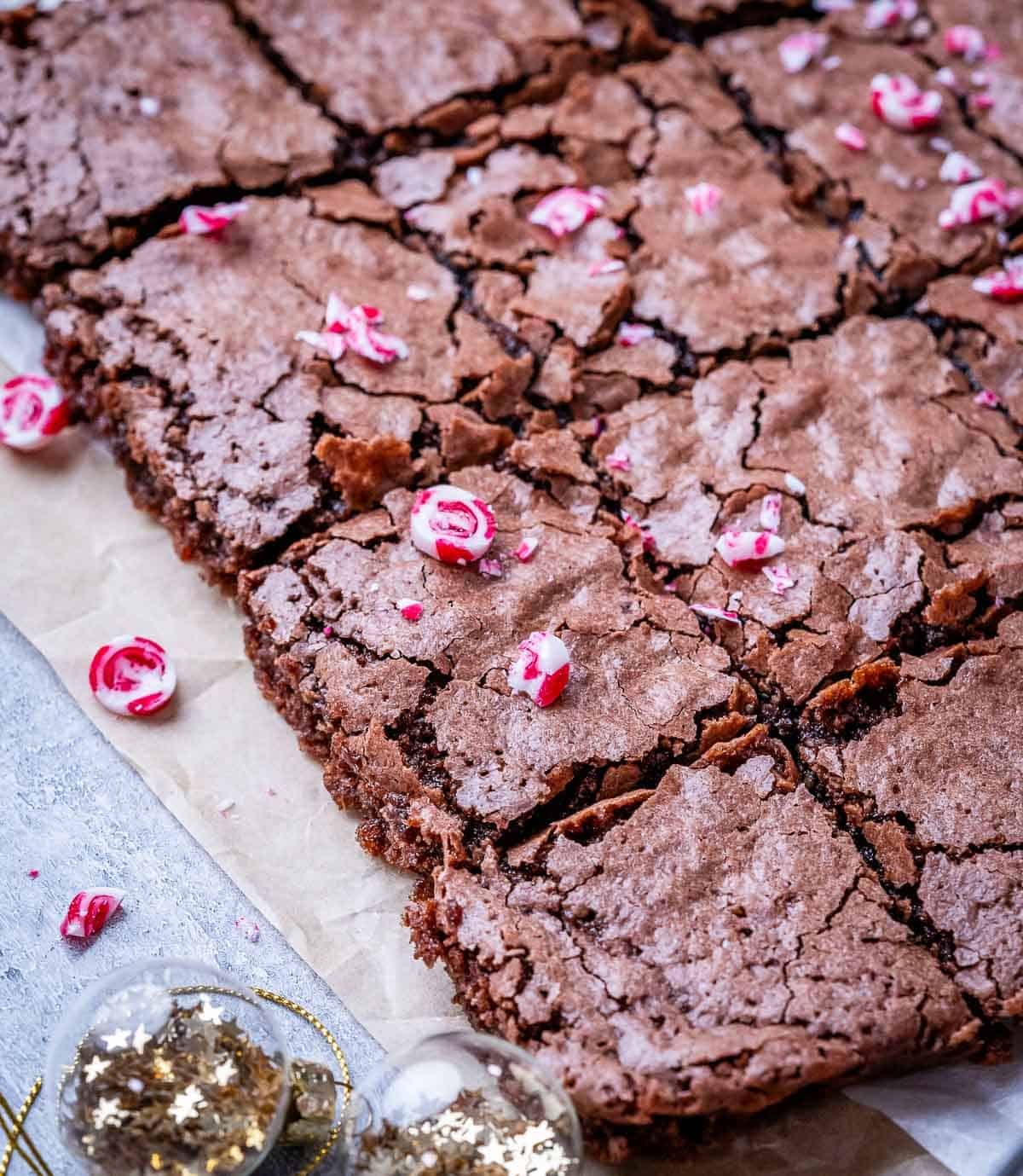 Close-up of baked peppermint brownies with crackly tops and scattered crushed candy canes.