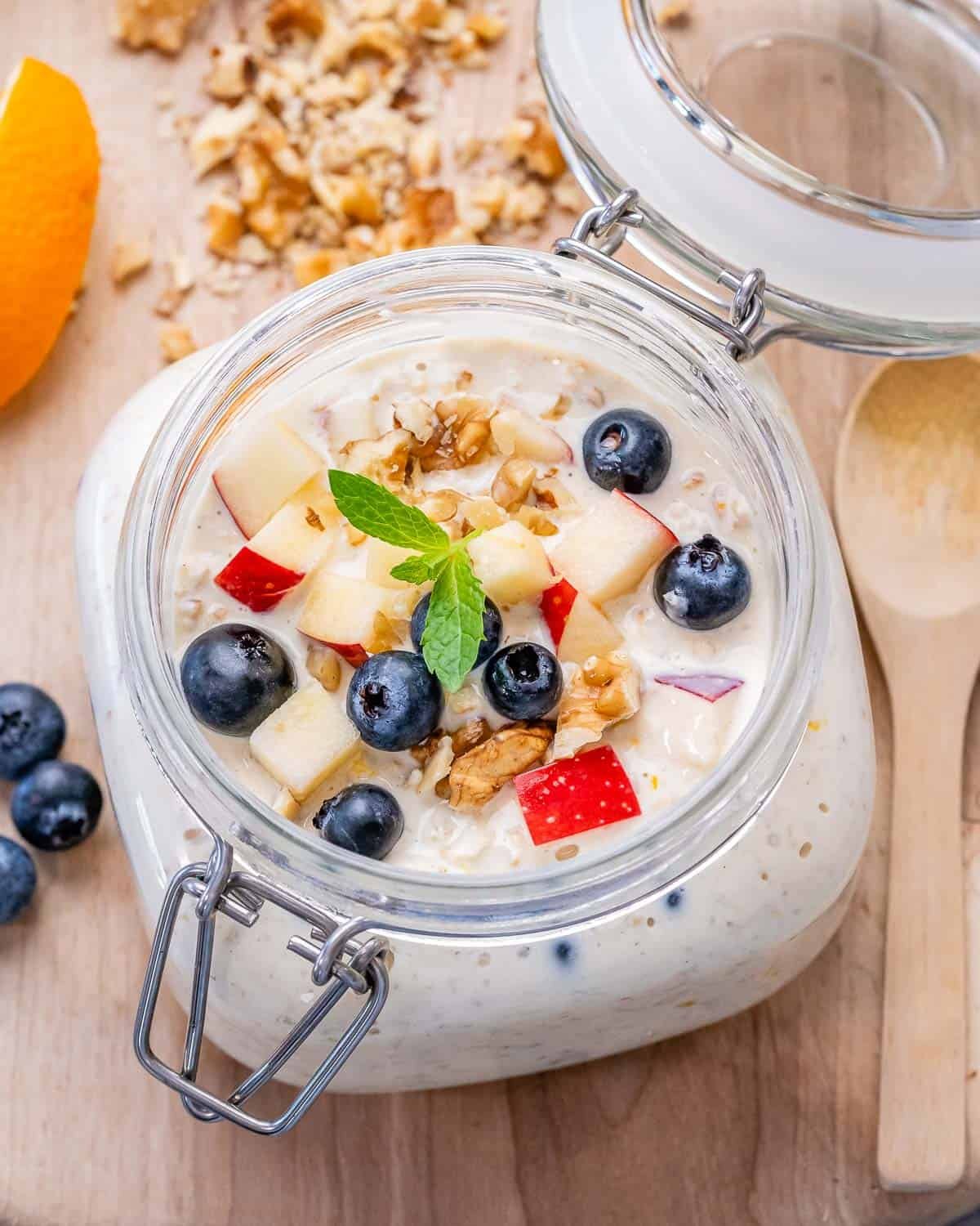 a jar filled with overnight oats topped with chopped apples and blueberries.