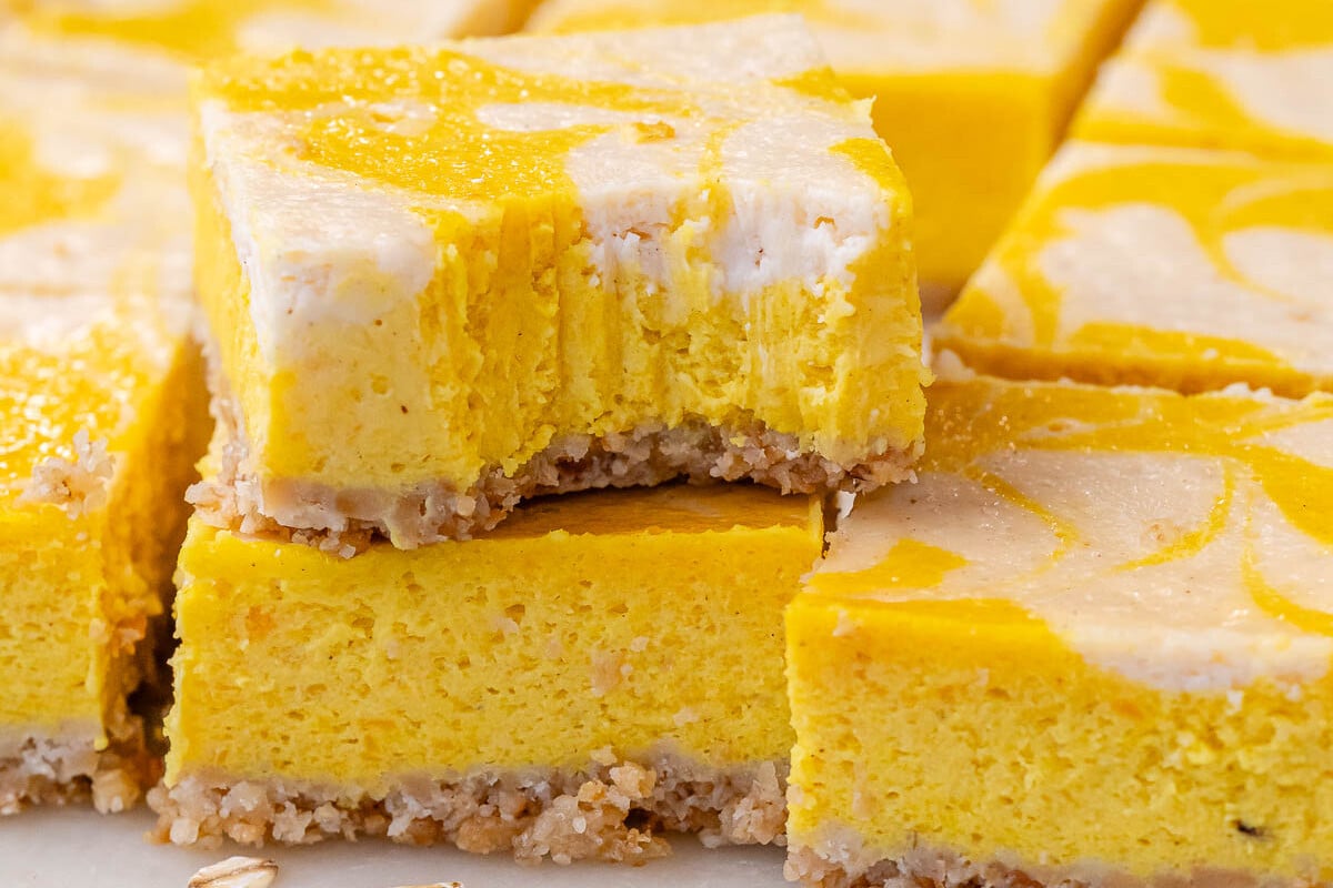 Bite shot of pumpkin cheesecake bar showing creamy texture and clean, defined layers.