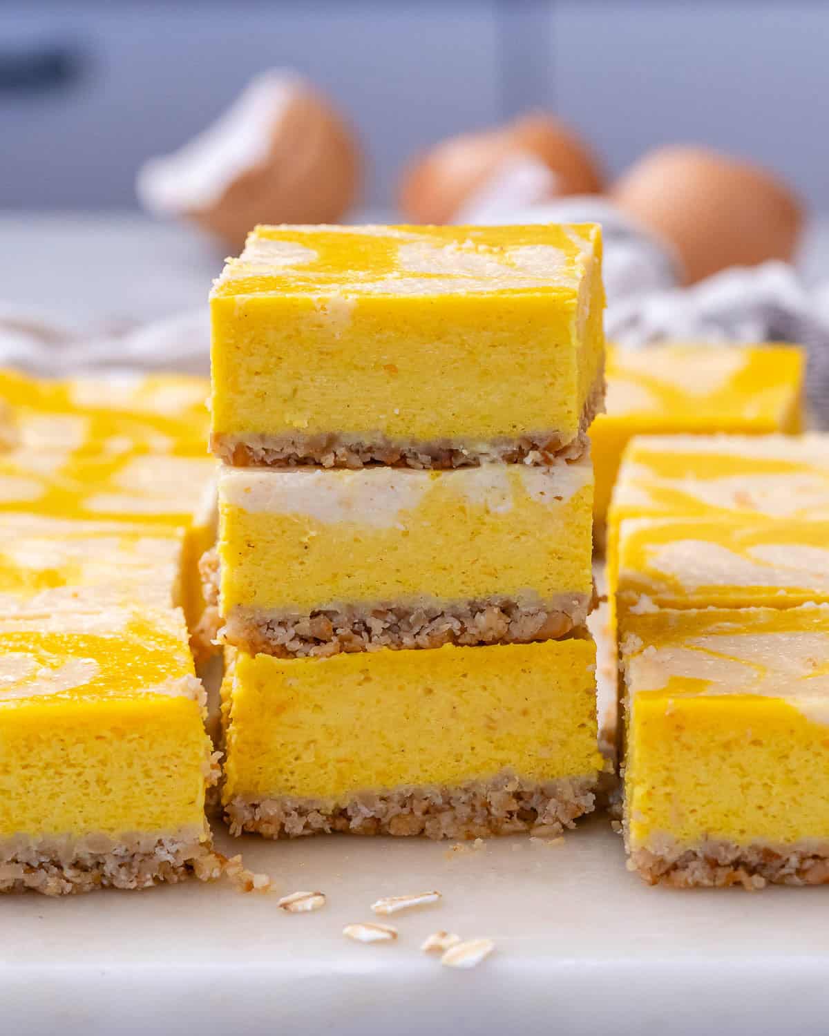 Tall stack of pumpkin cheesecake bars arranged neatly to display the layers and vibrant pumpkin color.