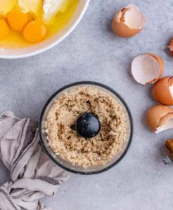Food processor blending oats, cashews, salt, sugar, and coconut oil to make the oat and cashew crust.