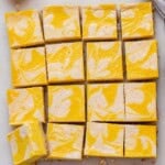 Pumpkin cheesecake slab freshly baked and cooling in the pan, cut into clean, even squares with a pretty marbled swirl on top.