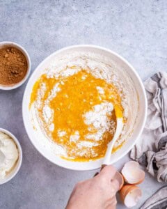 spatula mixing flour with the wet pumpkin batter.