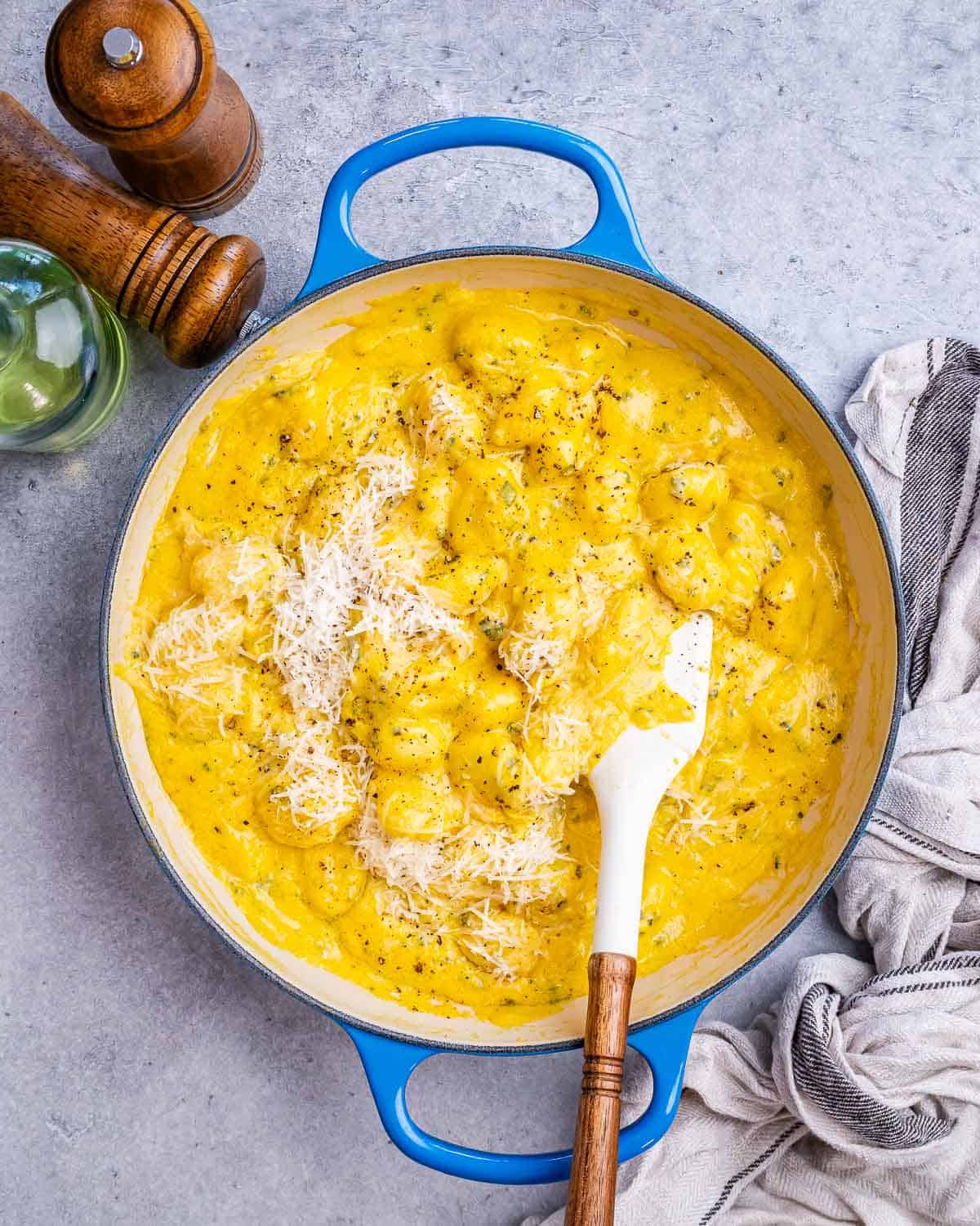 A blue skillet with pumpkin gnocchi and a white spatula.