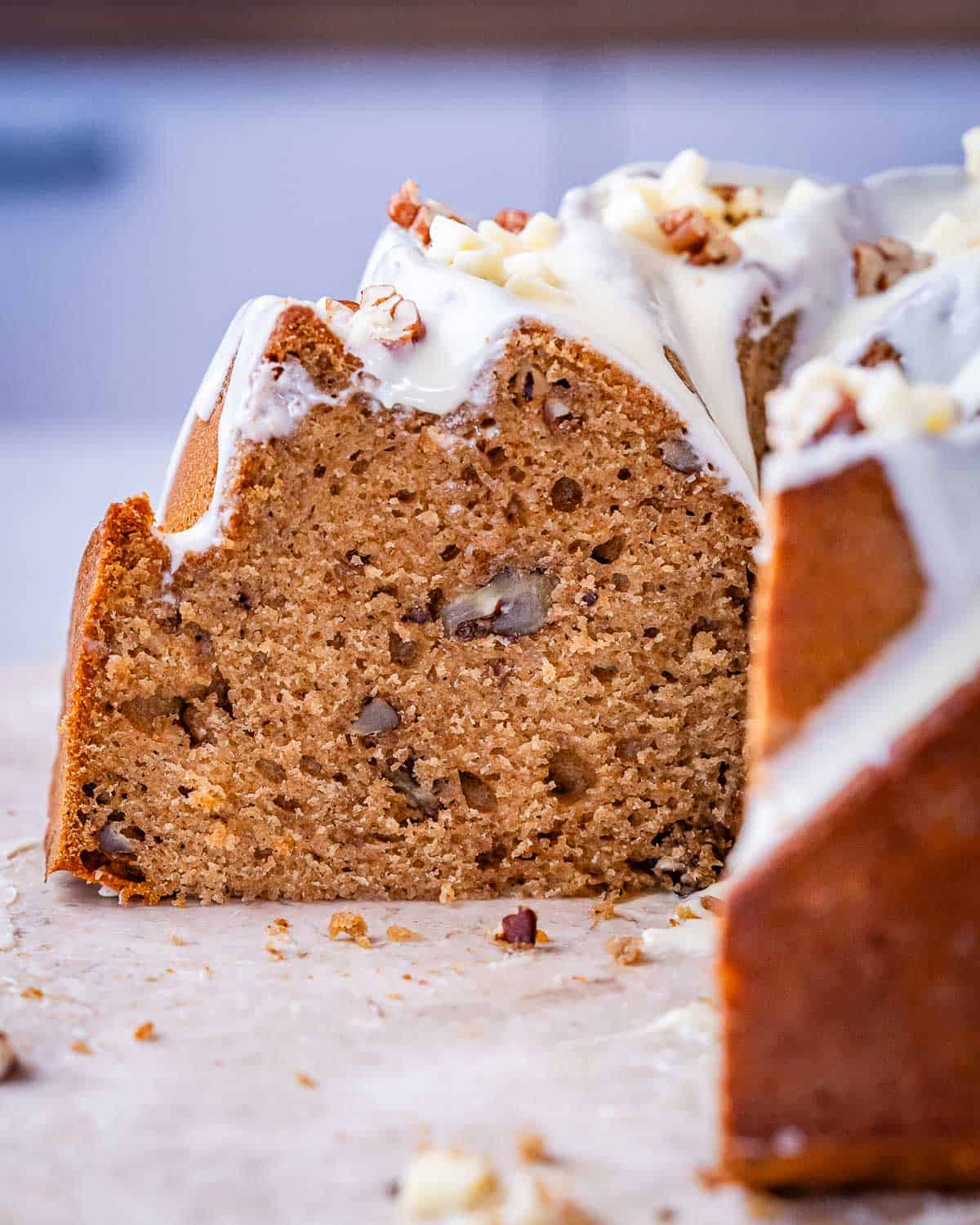 Close-up of the inside of the sweet potato Bundt cake showing its moist, tender crumb with bits of pecans, topped with creamy white chocolate glaze.