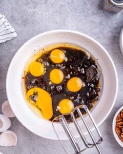 Ingredients including eggs, sugar, and coconut oil whisked together in a bowl to start the cake batter.