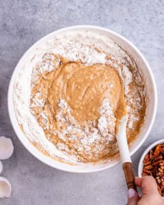 Wet and dry ingredients combined in a mixing bowl, forming a smooth, thick cake batter.
