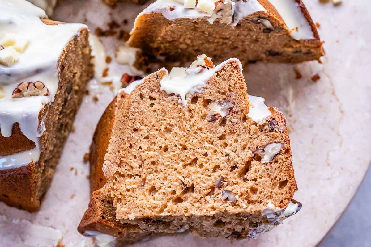 Close-up of a thick slice of sweet potato cake showing its soft, fluffy texture and bits of pecan inside.