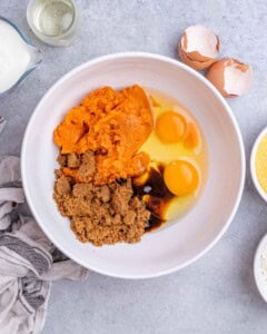 A mixing bowl filled with mashed sweet potato, brown sugar, eggs, and oil ready to be whisked together for the cornbread batter.