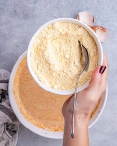 Cornmeal being added to the wet sweet potato mixture to form the cornbread batter.