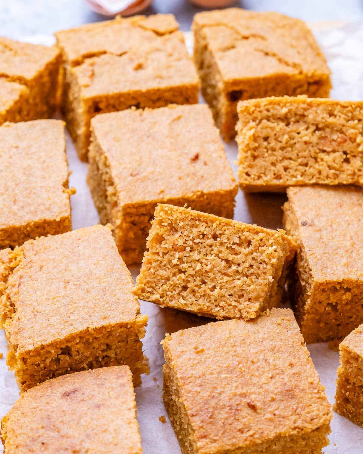 Freshly baked sweet potato cornbread cut into even squares, showing the soft, fluffy crumb and golden-brown edges.