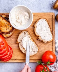 Mayo being spread over toast.