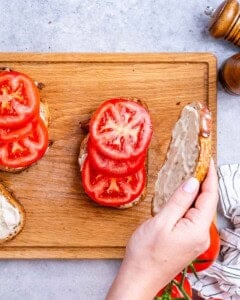 assembling the sandwich with the sliced tomatoes on the toast.