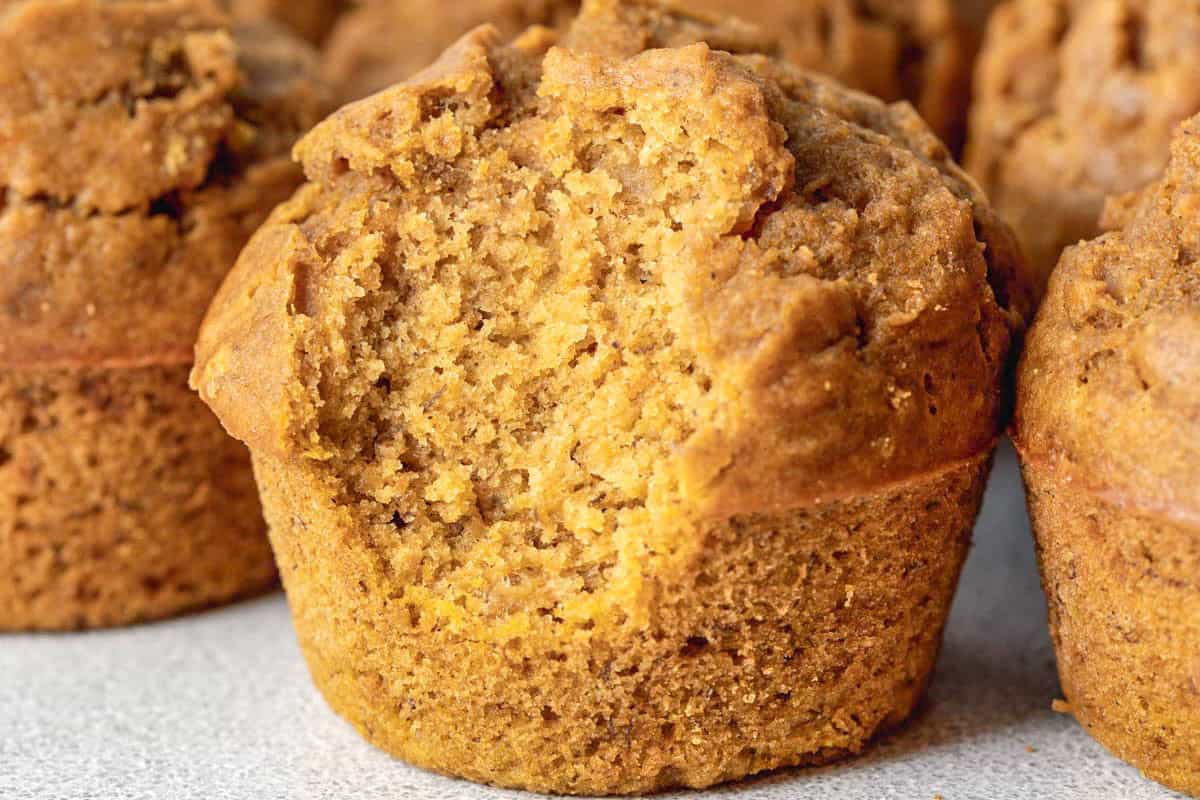 a single muffin set on a flat surface and a bite taken off.