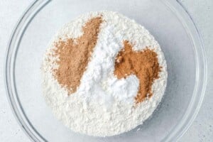 adding dry ingredients to a bowl to make pumpkin banana muffins.