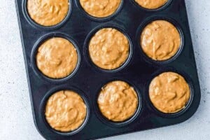 Batter being placed in a muffin pan.