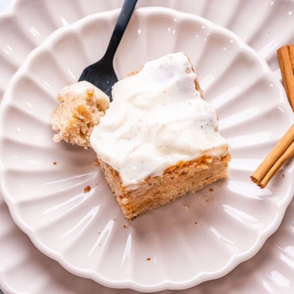 a cinnamon roll cake portion on a plate with a fork on it.