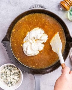 cream cheese added over the seasoned broth in the black skillet.
