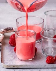 Jello and yogurt liquid are being added to a cup.