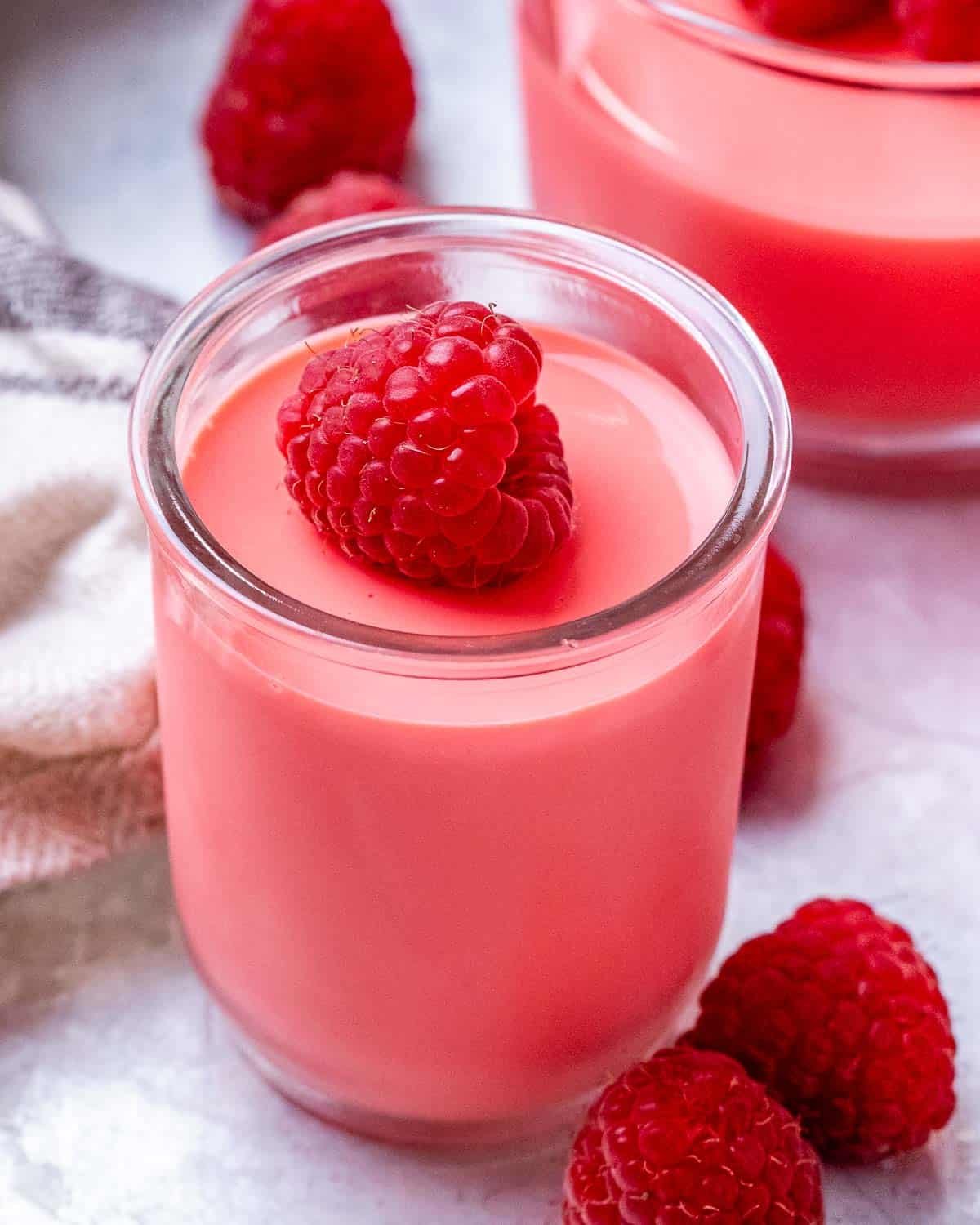 a cup with yogurt jello topped with a raspberry