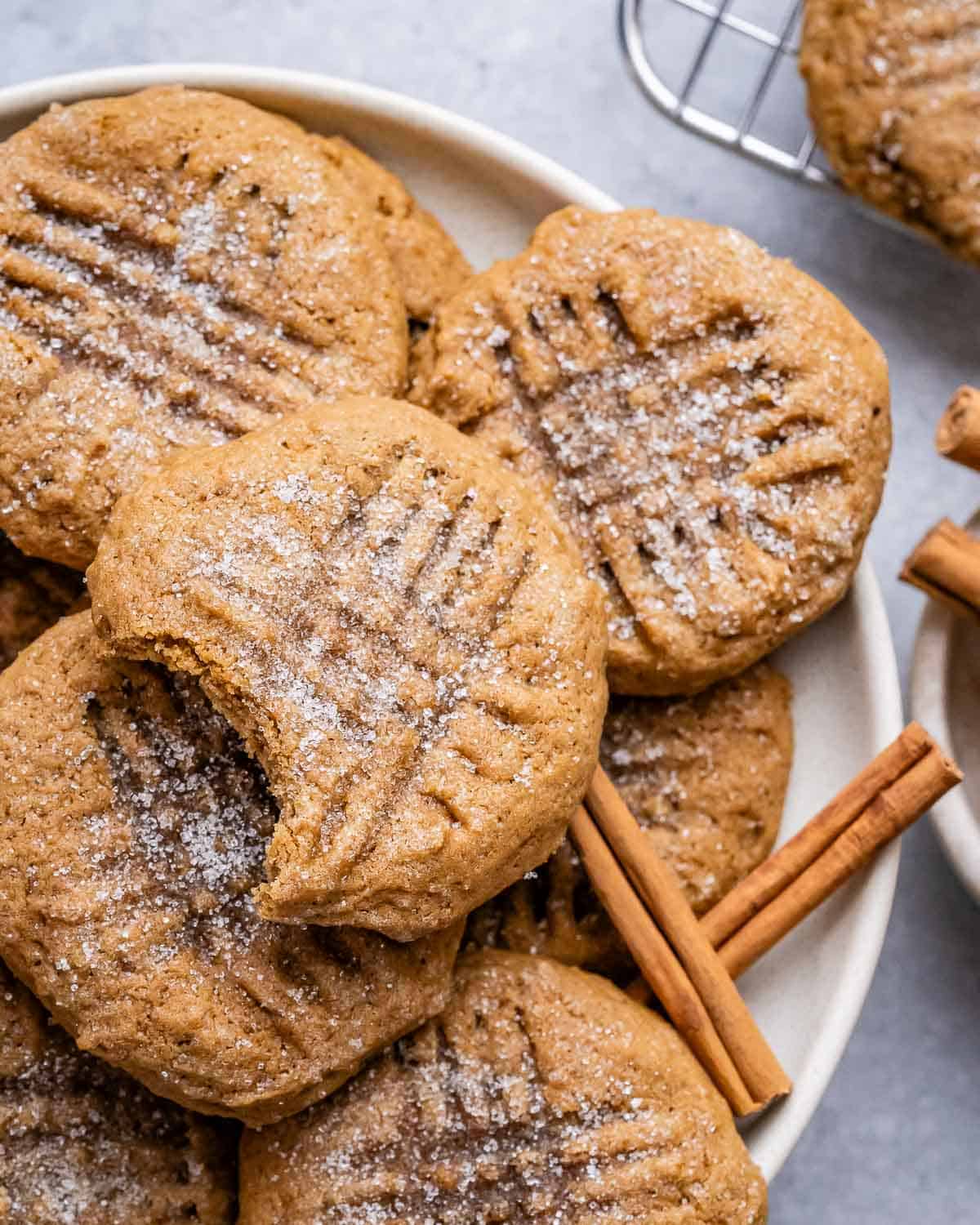 A pile of gingerbread cookies, one with a bite taken out, on a white plate.