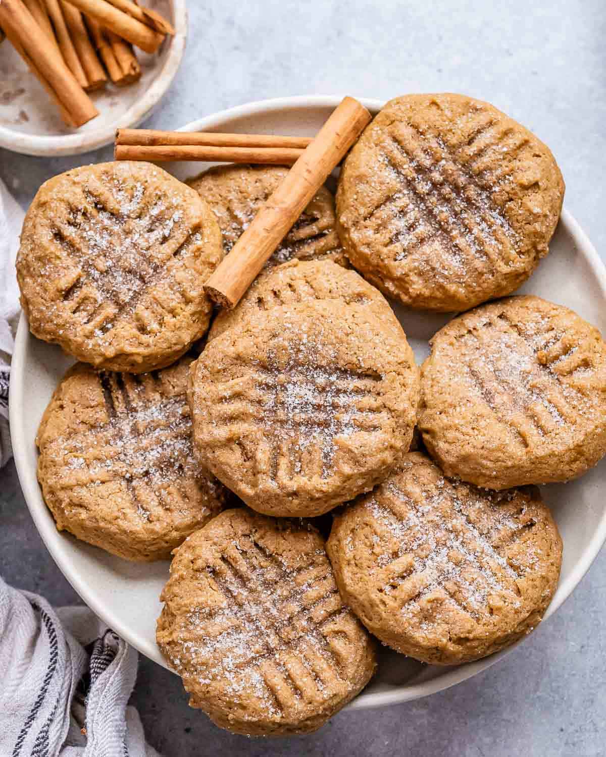 Gingerbread cookies on a white plate with cinnamon sticks.