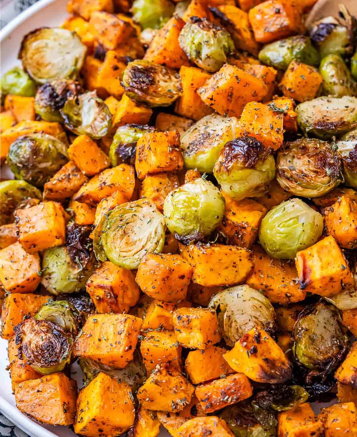 A close-up image of roasted, cubed sweet potatoes and Brussels sprouts.