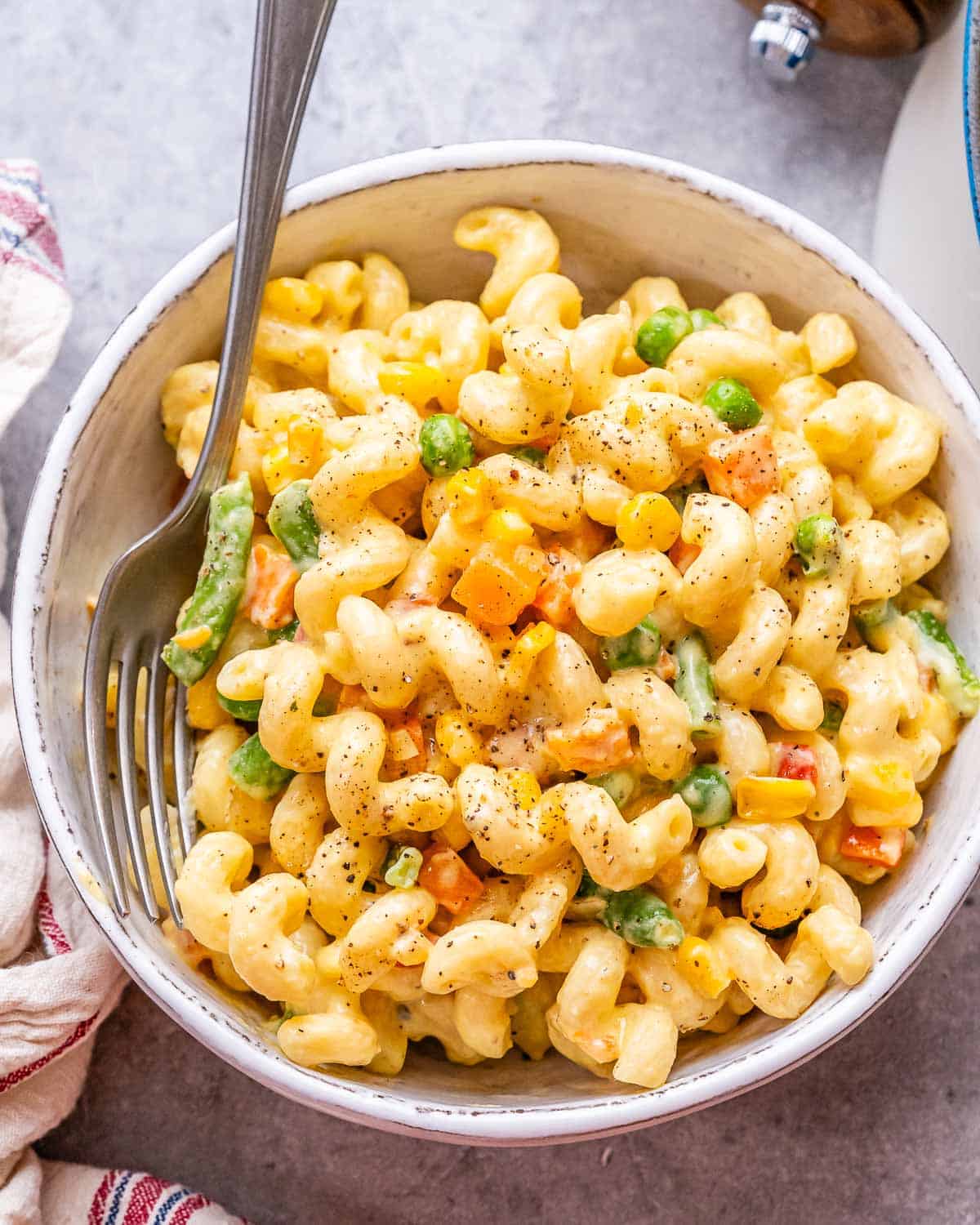 Veggie mac and cheese in a white ceramic bowl with a fork.