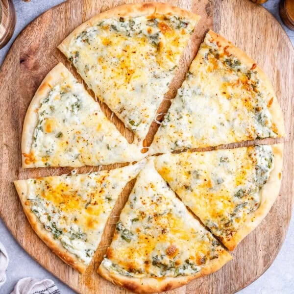 a pizza sliced into 6 pieces on a wooden cutting board.